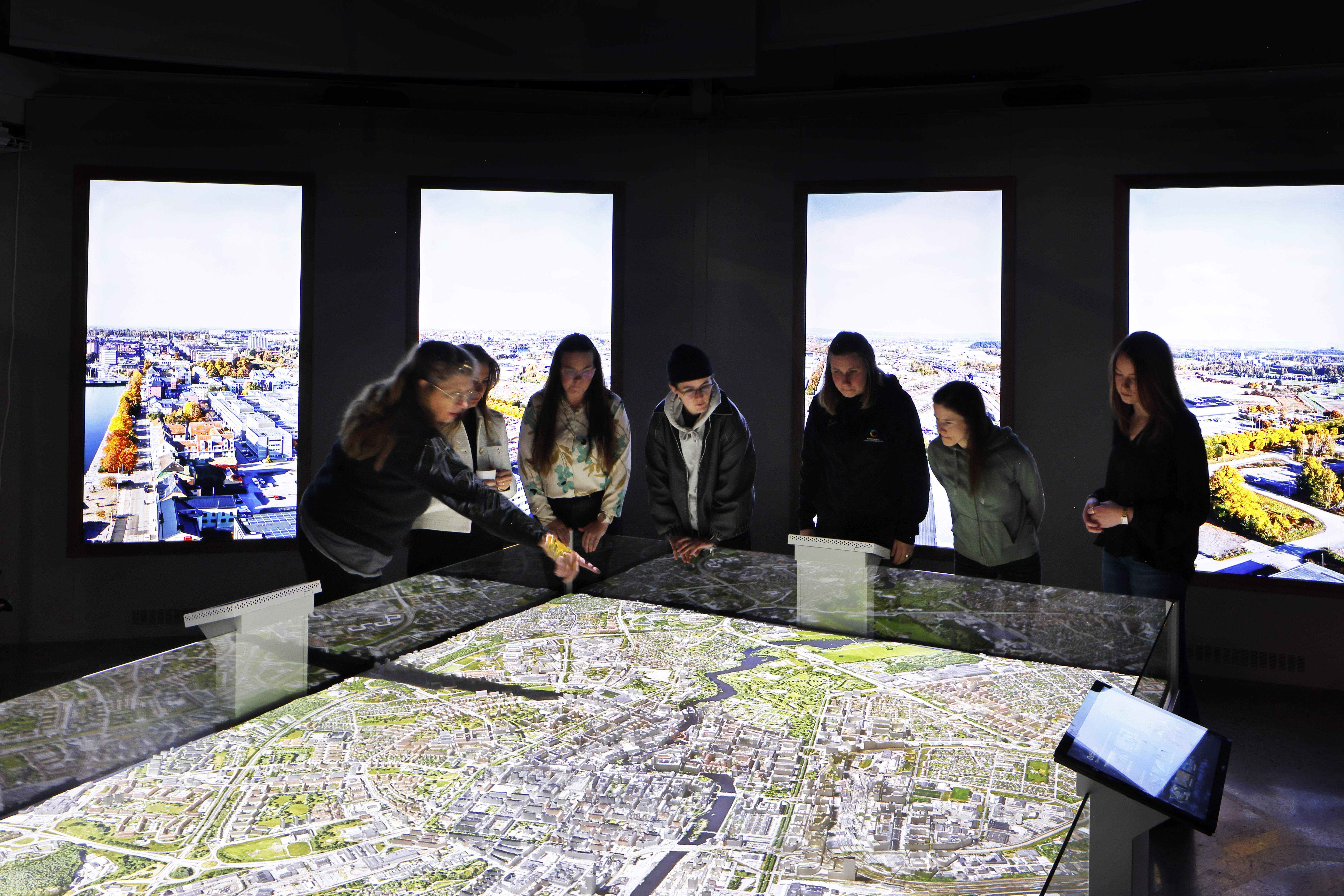 Four vertical wall displays mounted beside the SimStad city model
